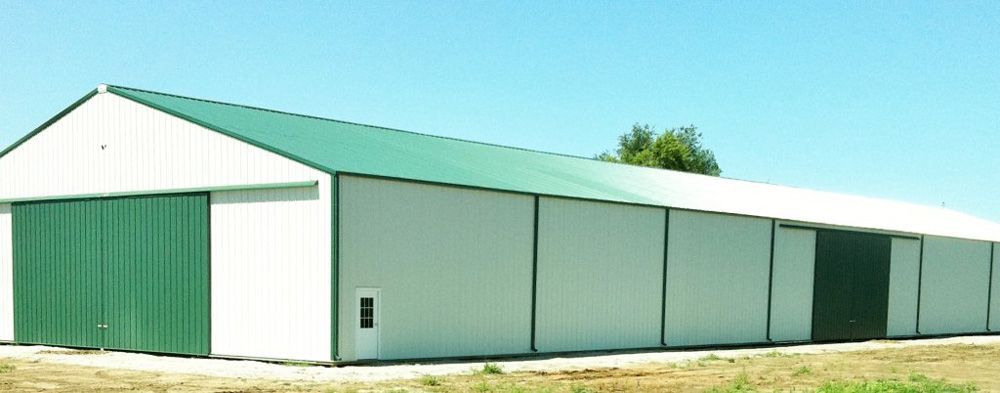 A white building with a green roof and green doors
