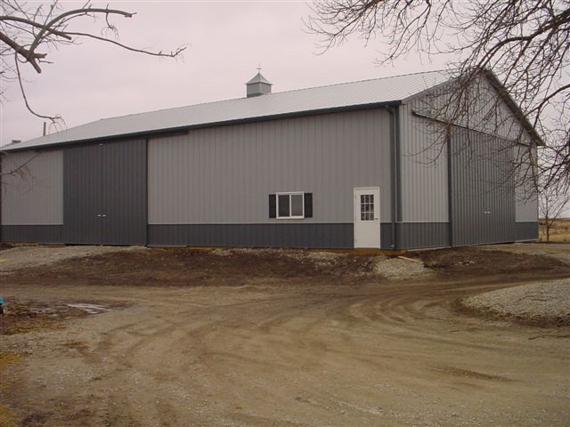 A gray and black barn with a white door