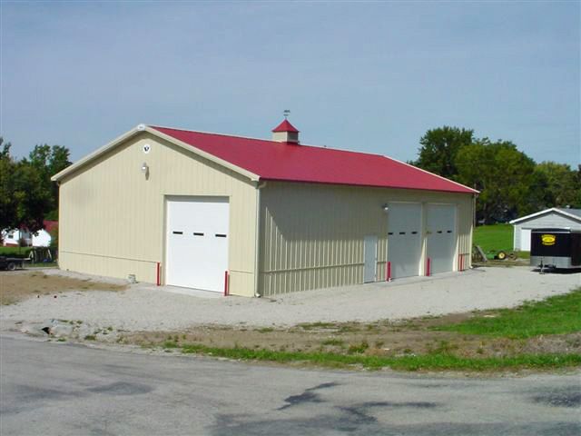 A tan building with a red roof and white doors