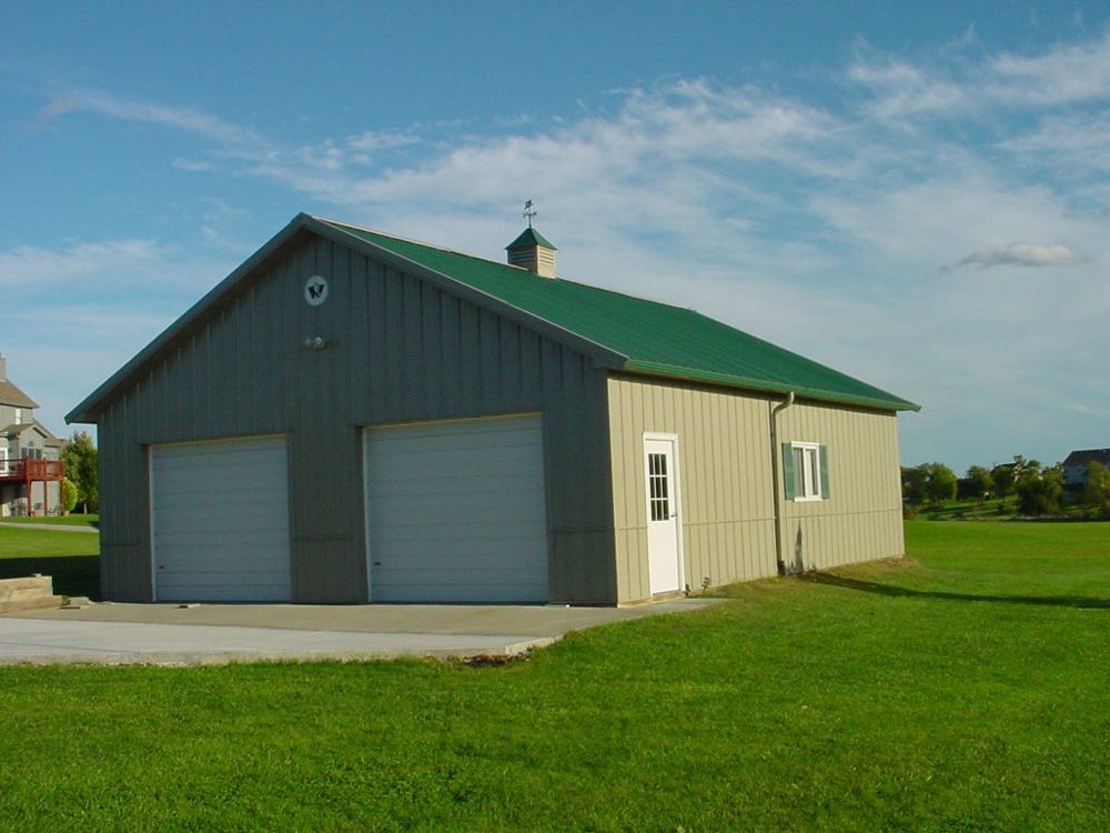 A garage with two garage doors and a green roof