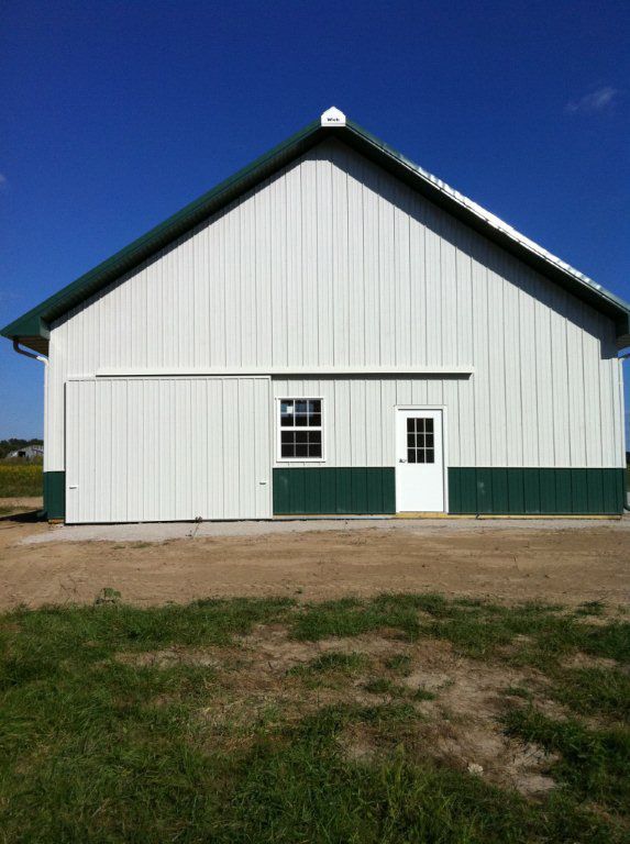 A white barn with green trim and a white door
