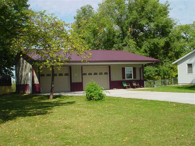 A garage with a purple roof and a white house in the background