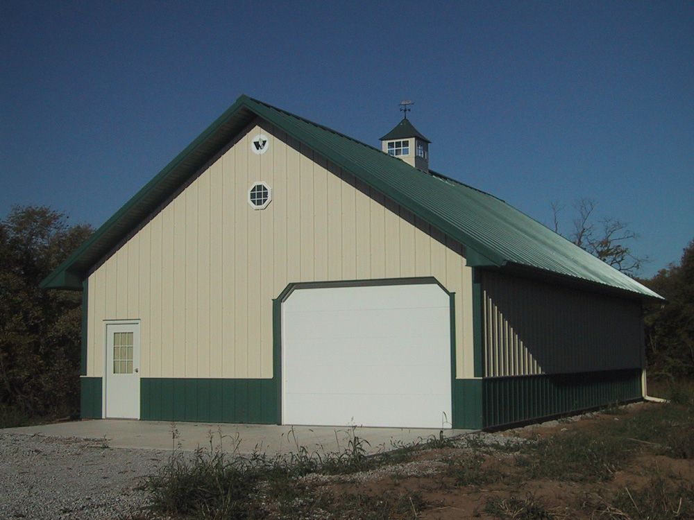 A barn with a green roof and a white door