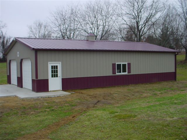 A large building with a purple roof is sitting in the middle of a grassy field.