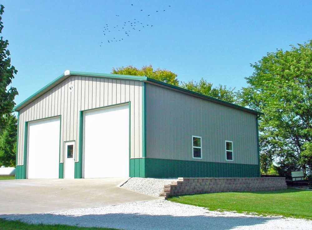 A large metal building with a green roof and white doors