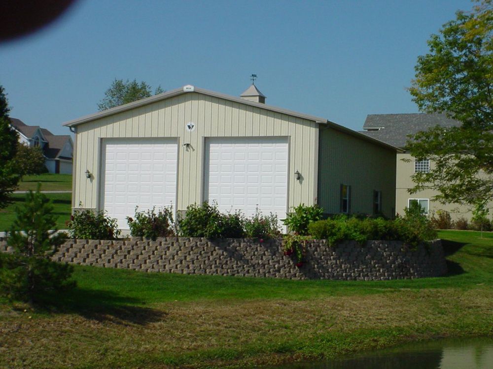 A garage with two white garage doors sits next to a pond
