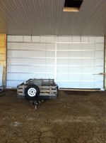 A trailer is parked in front of a garage door.