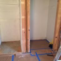 A partially constructed wooden doorway frame leading into an interior room under renovation with floors covered in brown paper.