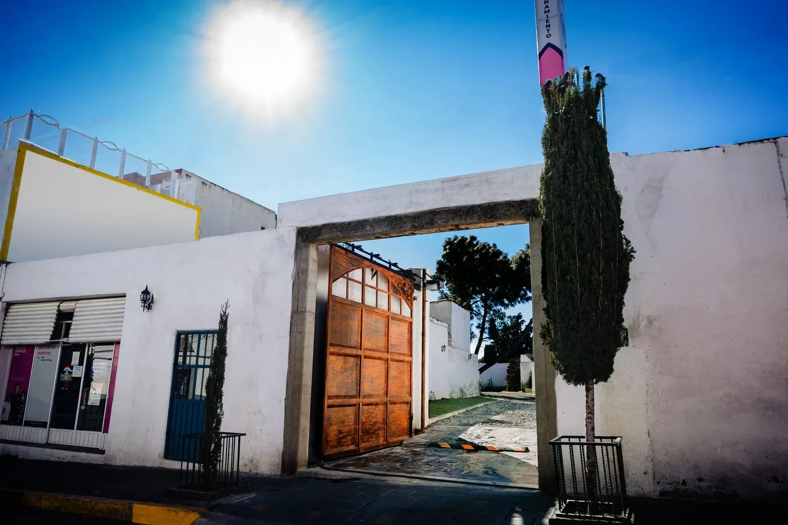 Un edificio blanco con una puerta marrón y un árbol delante.