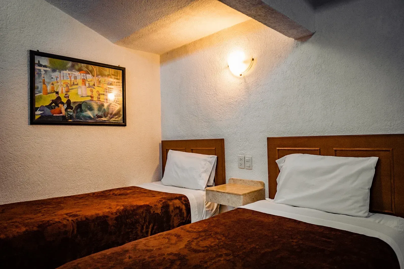A hotel room with two beds and a picture on the wall.