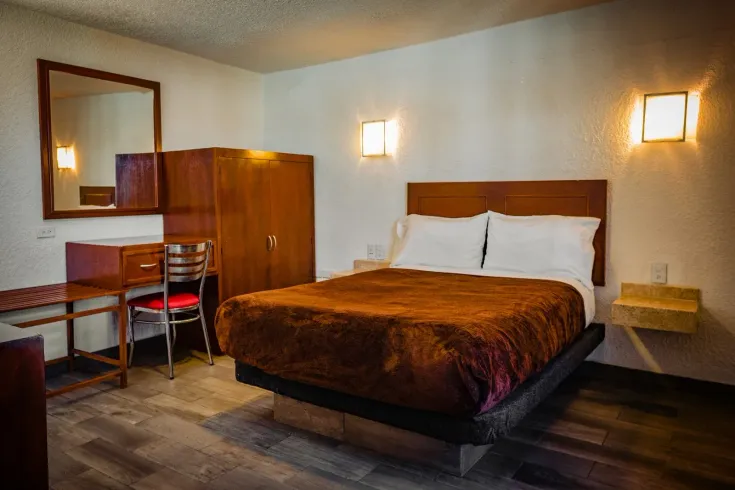 Una habitación de hotel con cama, escritorio, silla y espejo.