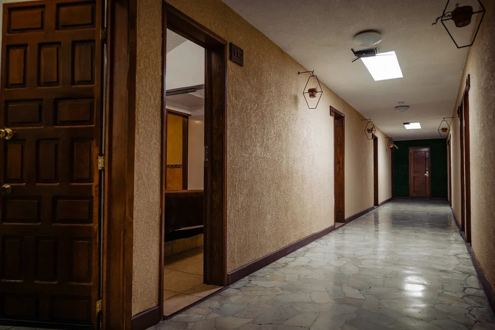 Un pasillo largo con muchas puertas y una luz en el techo.