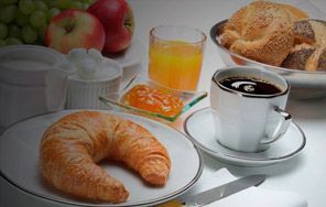Hay un croissant en un plato al lado de una taza de café.
