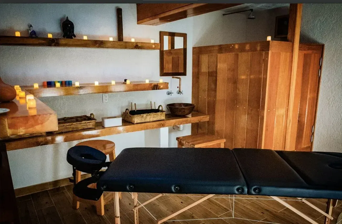 Una mesa de masajes en una habitación con velas en los estantes.