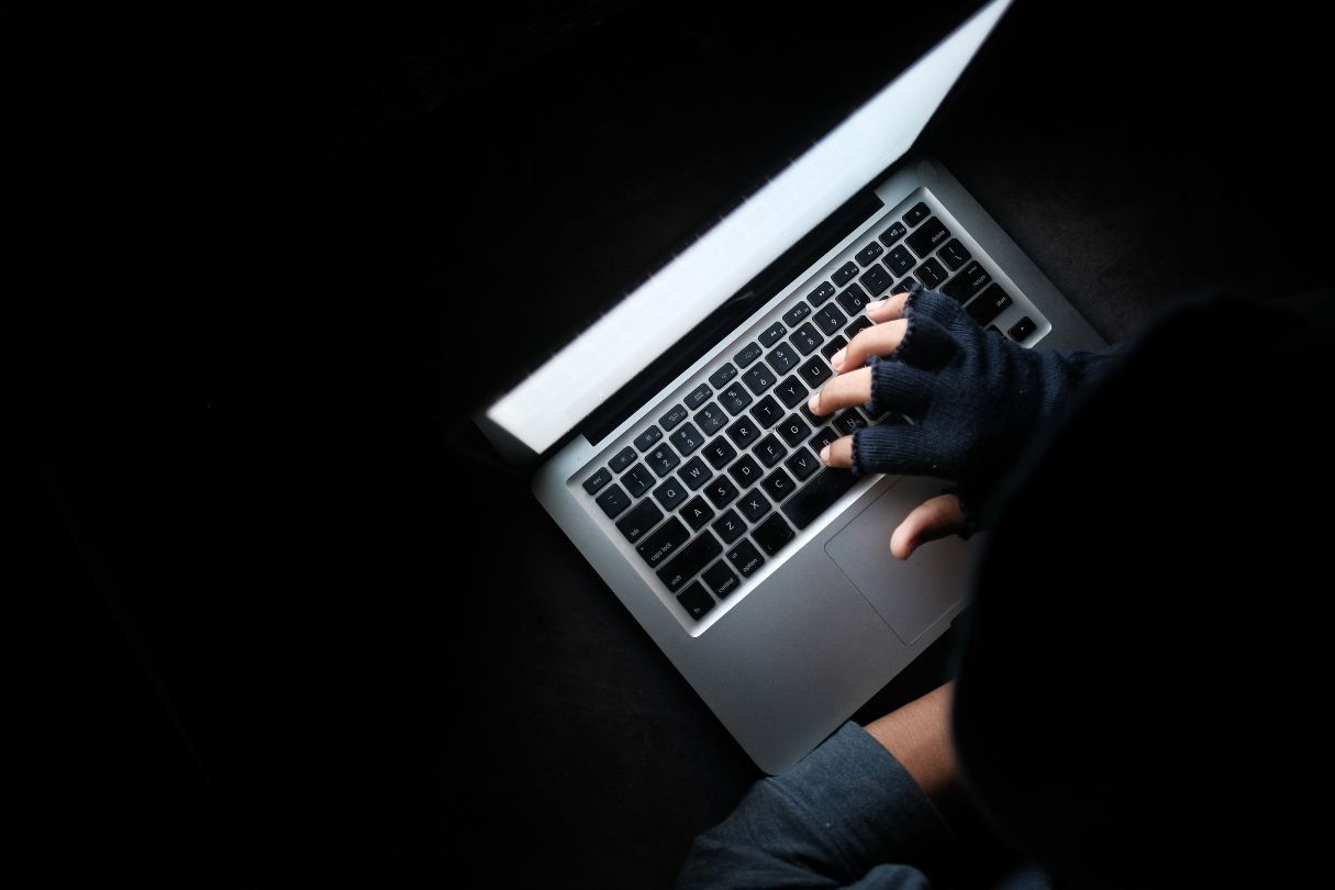 Website on a laptop in a dark room, with a person wearing fingerless gloves navigating it.