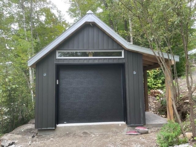 Un garage noir avec un toit gris et une porte de garage noire
