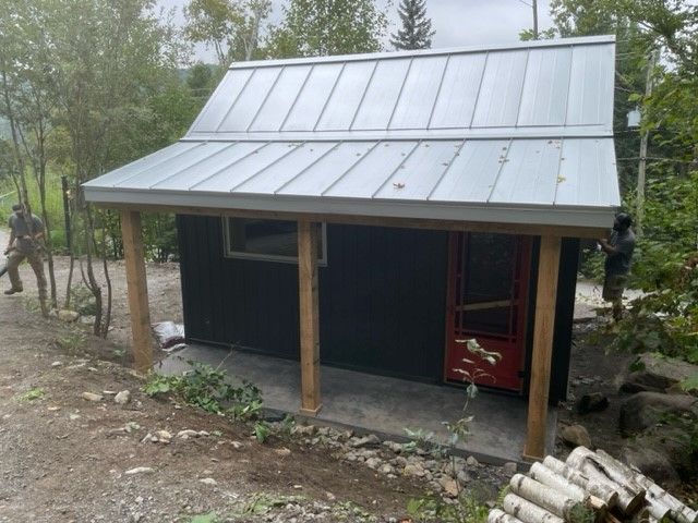 Une petite maison avec un toit en métal et un porche en bois.