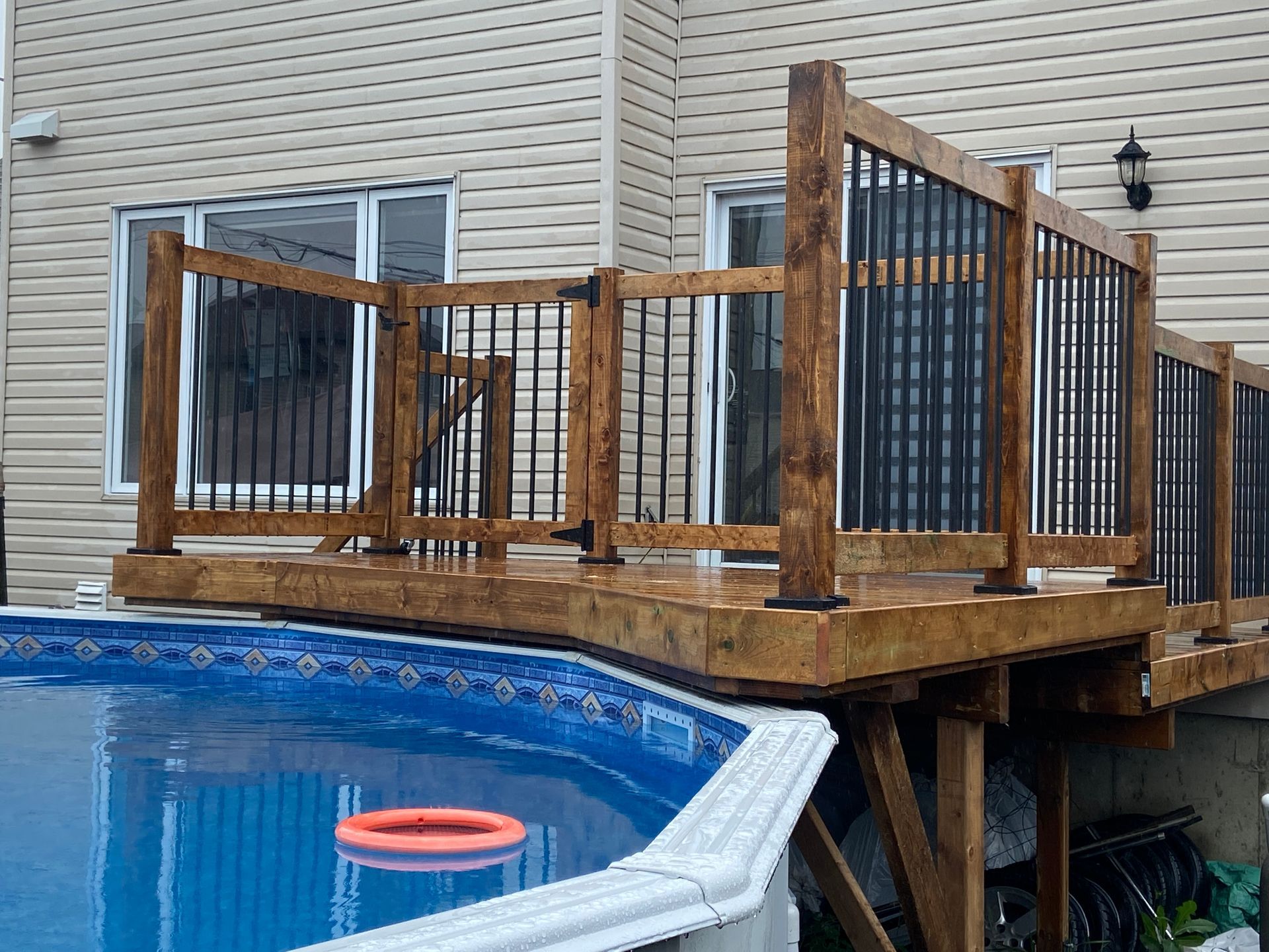 Une terrasse en bois donnant sur une piscine à côté d'une maison.