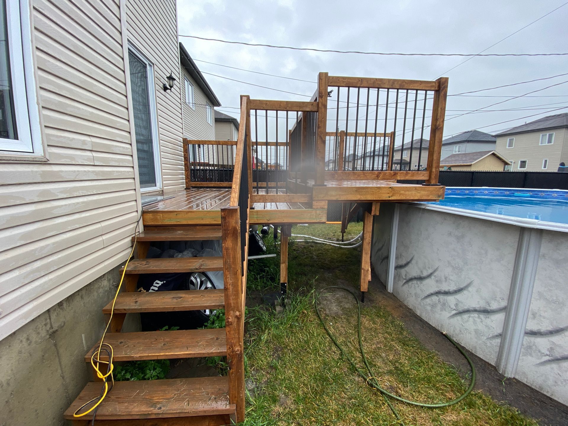 Une terrasse en bois avec des escaliers qui y mènent à côté d'une piscine.