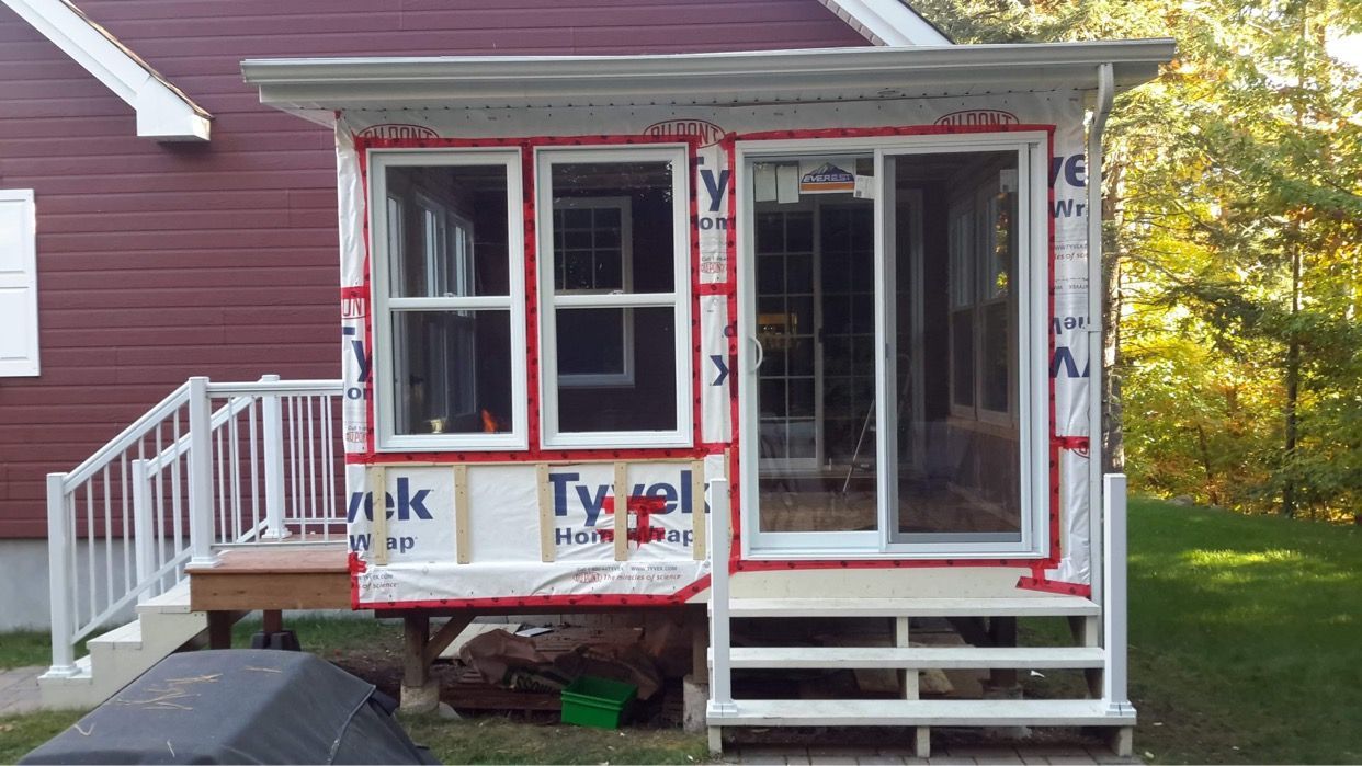 Une petite maison avec une véranda grillagée est en cours de construction.