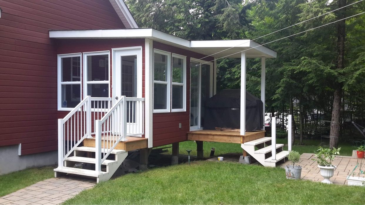 Une maison rouge avec une véranda et des escaliers