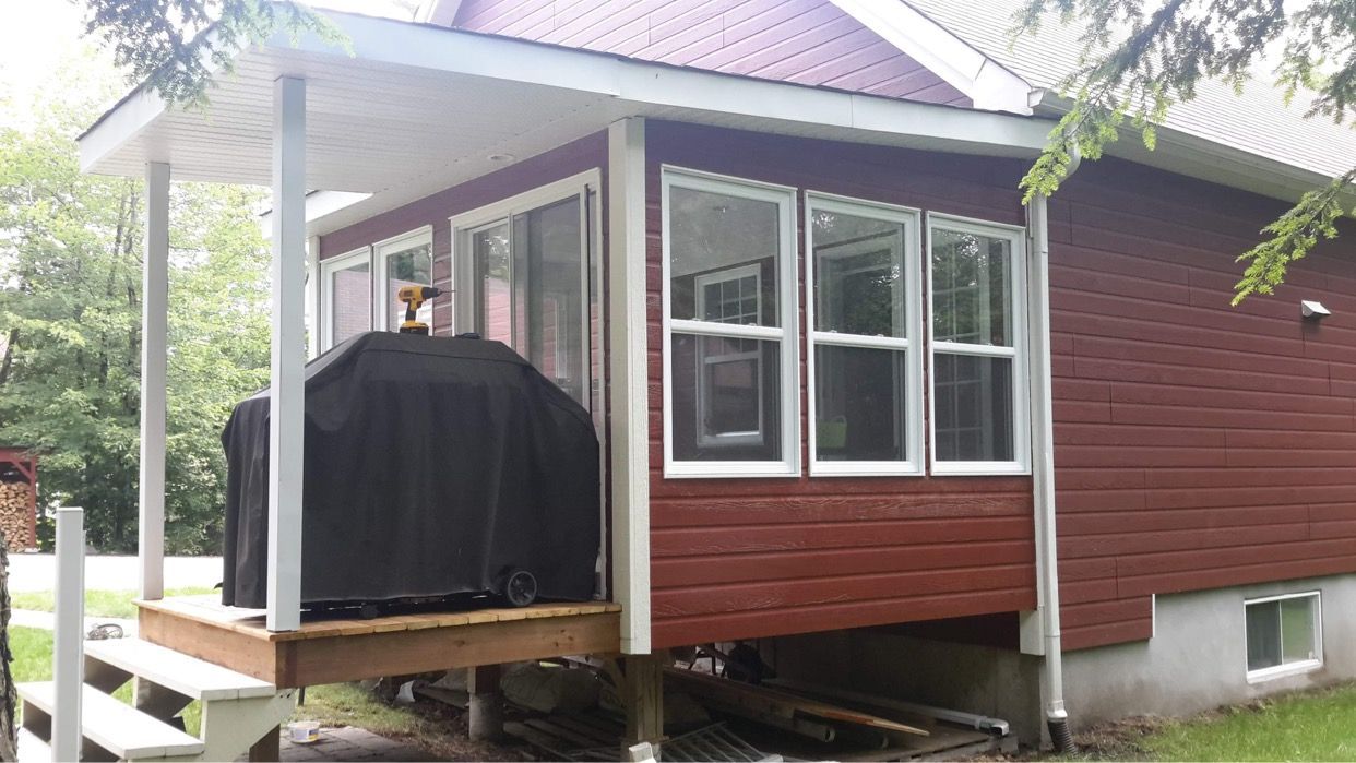 Une petite maison rouge avec une véranda et des escaliers.