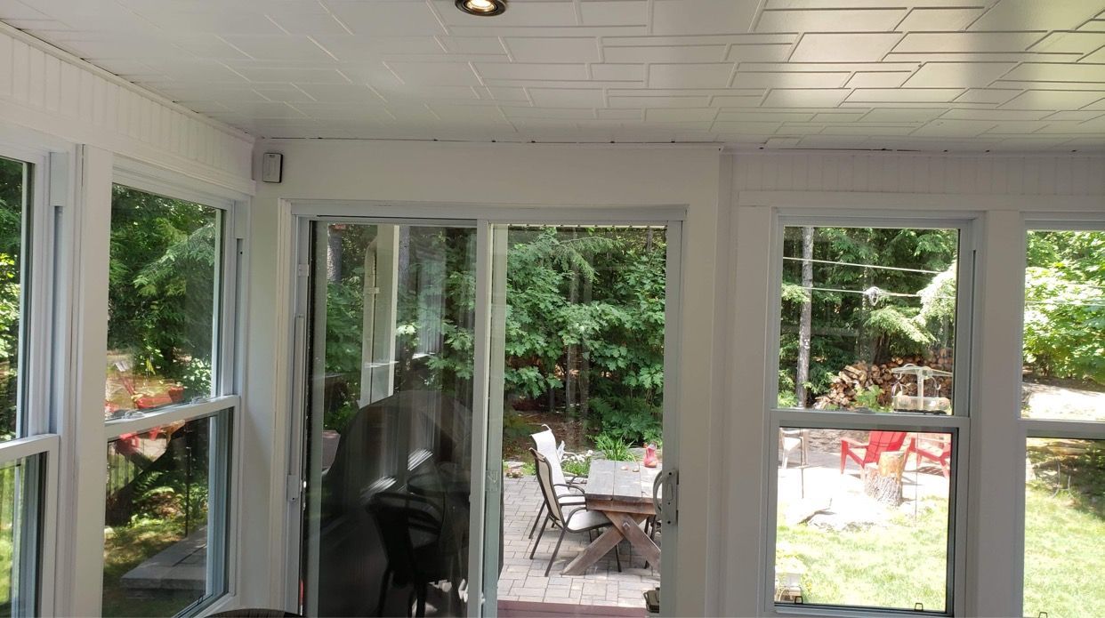 Une pièce avec beaucoup de fenêtres et une porte coulissante en verre donnant sur un patio.