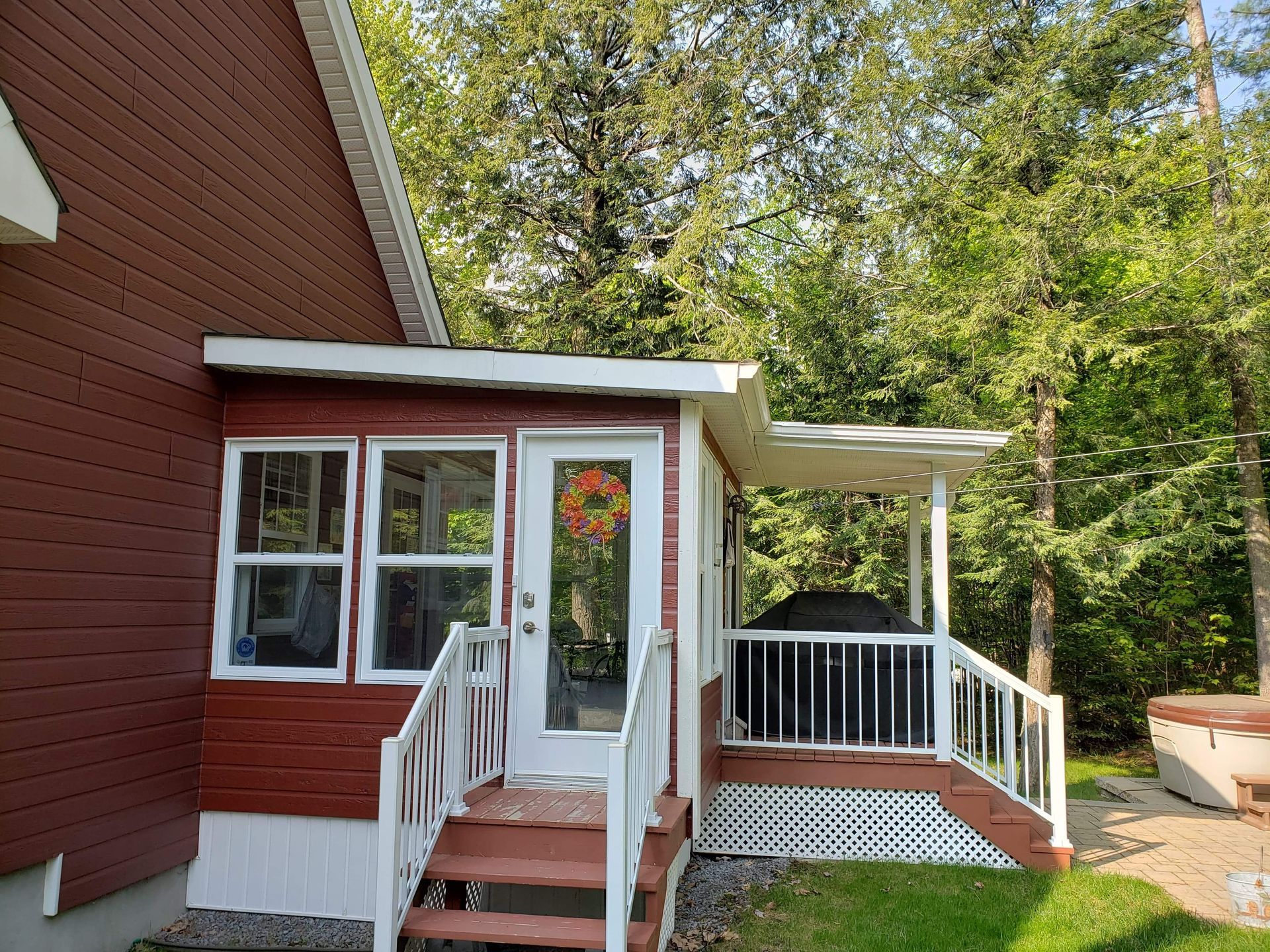 Une maison rouge avec un porche et des escaliers qui y mènent.