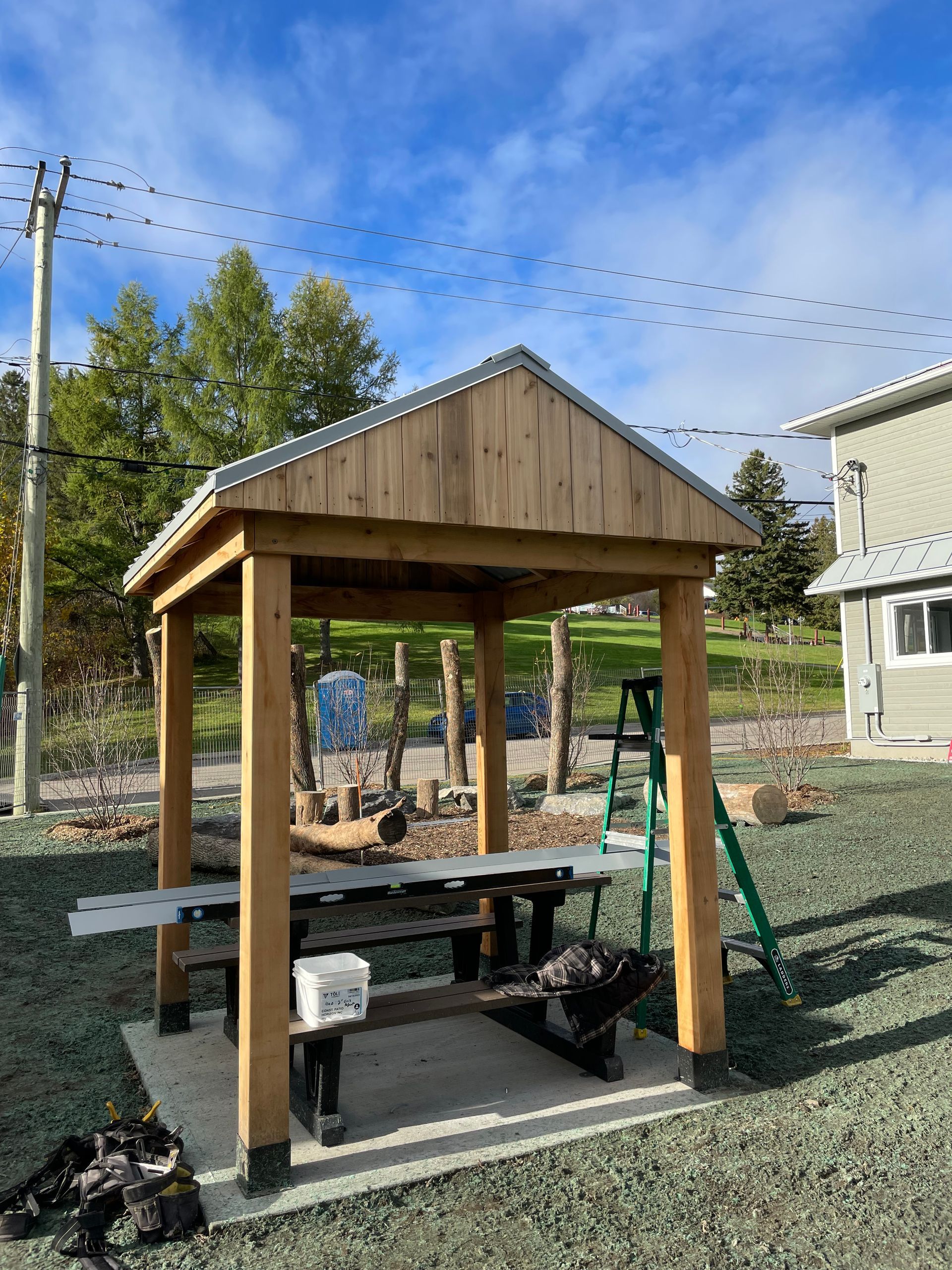 Un belvédère en bois avec une table de pique-nique et des bancs en dessous.