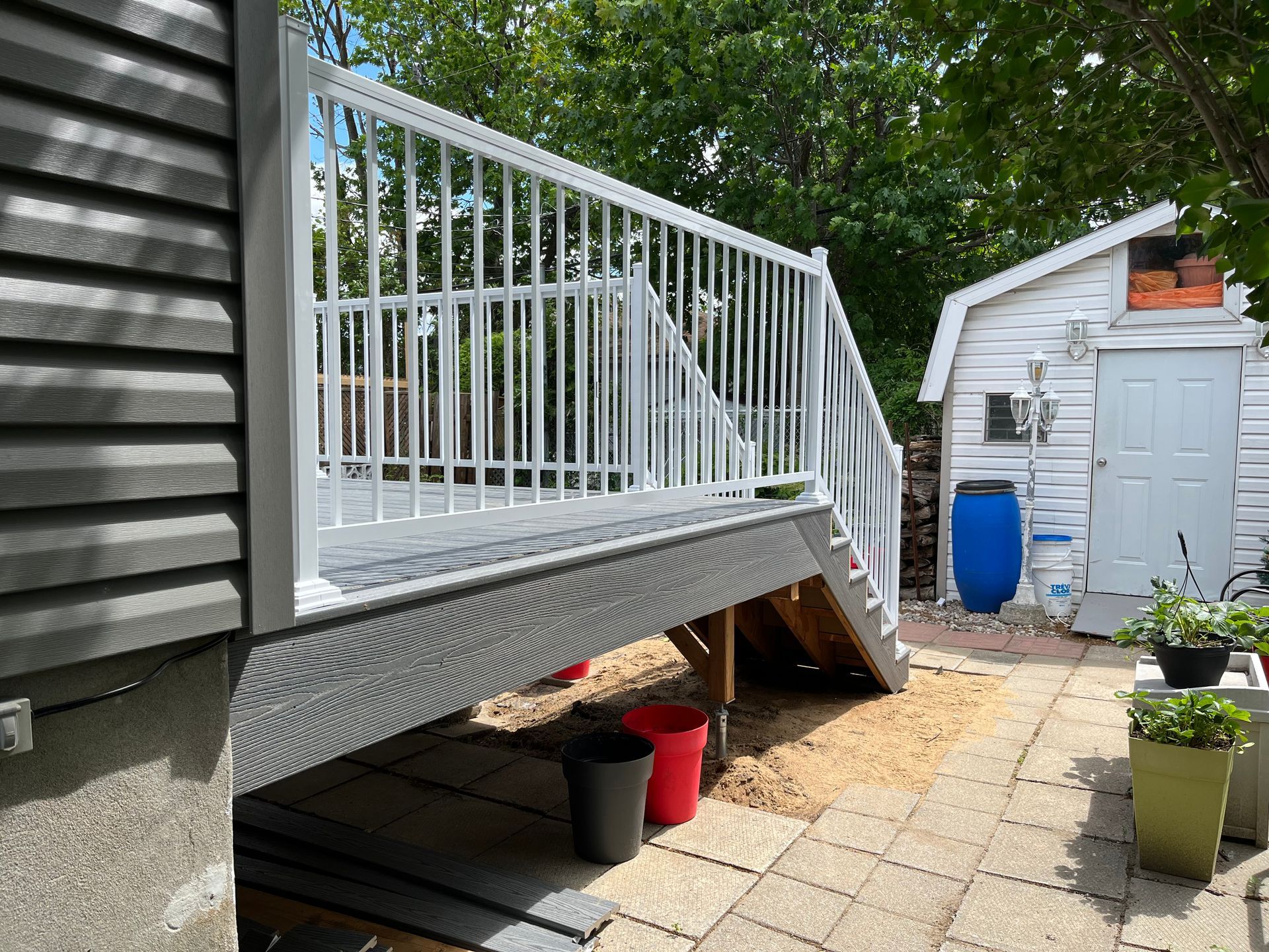 Une terrasse blanche avec des escaliers qui y mènent à côté d'un hangar blanc.