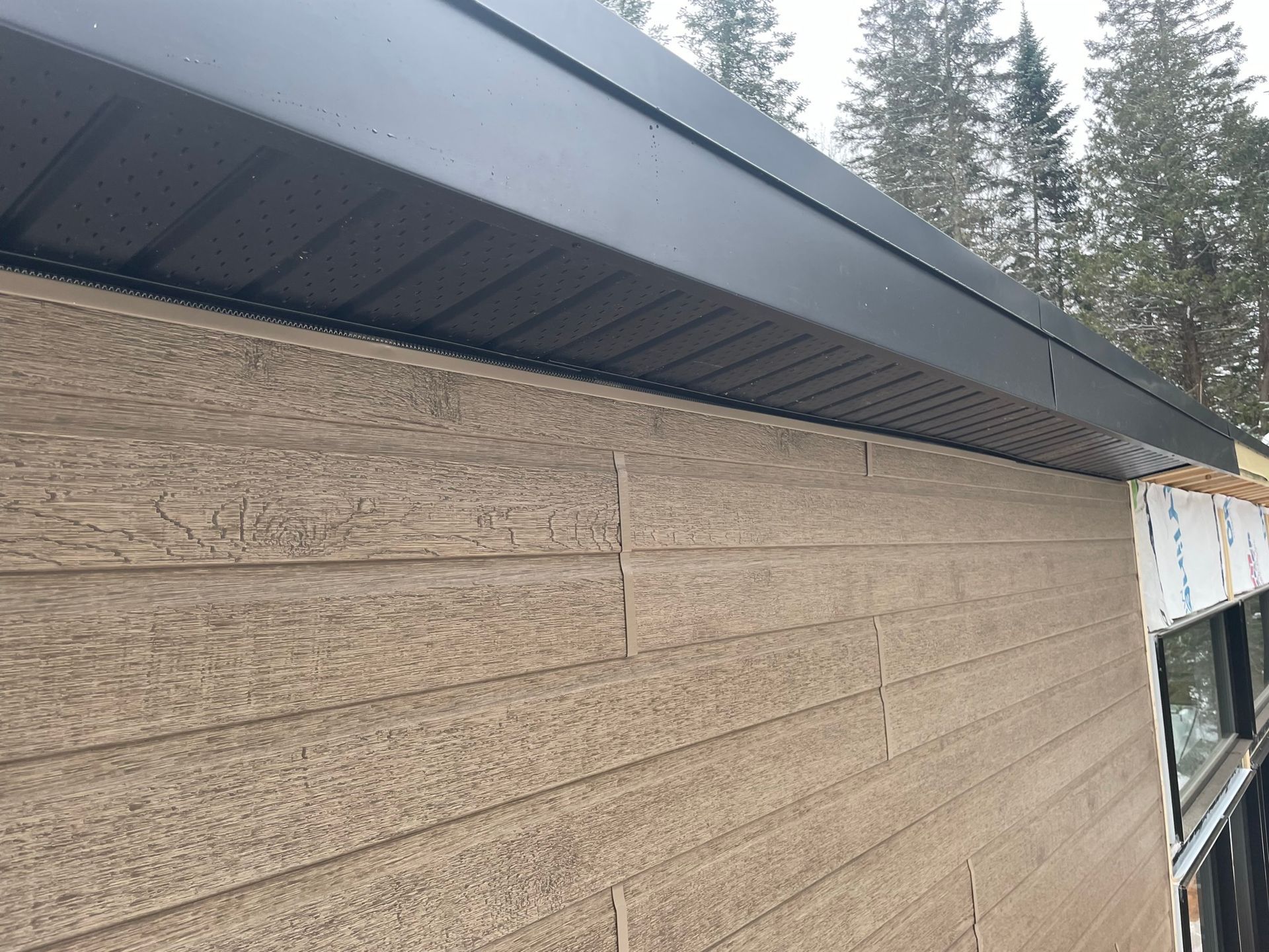 Une maison avec un bardage en bois et un toit noir.