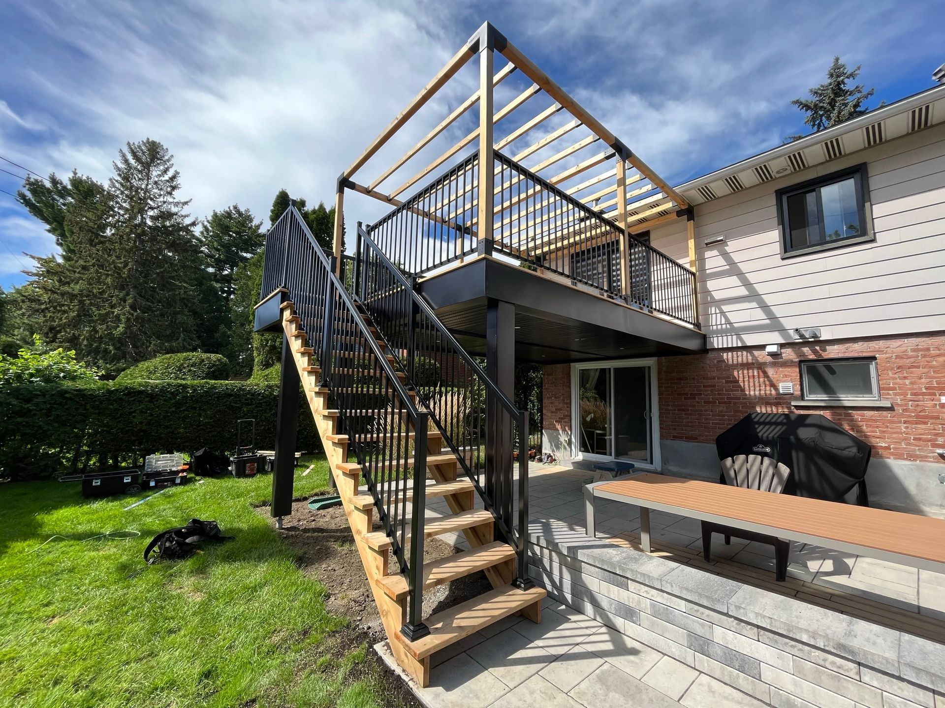 Une terrasse en bois avec des escaliers qui y mènent est en cours de construction dans la cour d'une maison.