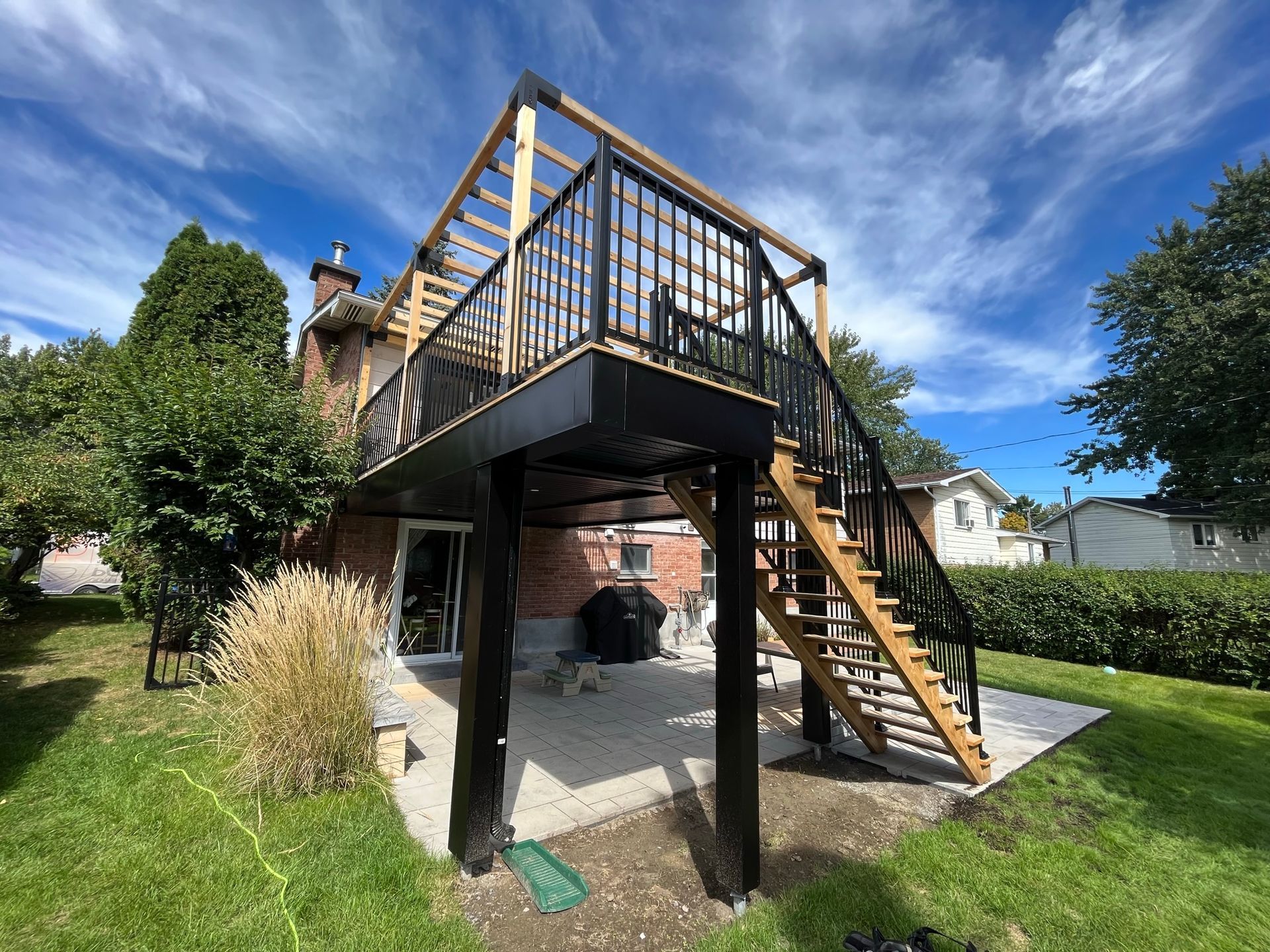 Une terrasse en bois avec des escaliers qui y mènent se trouve dans la cour d'une maison.