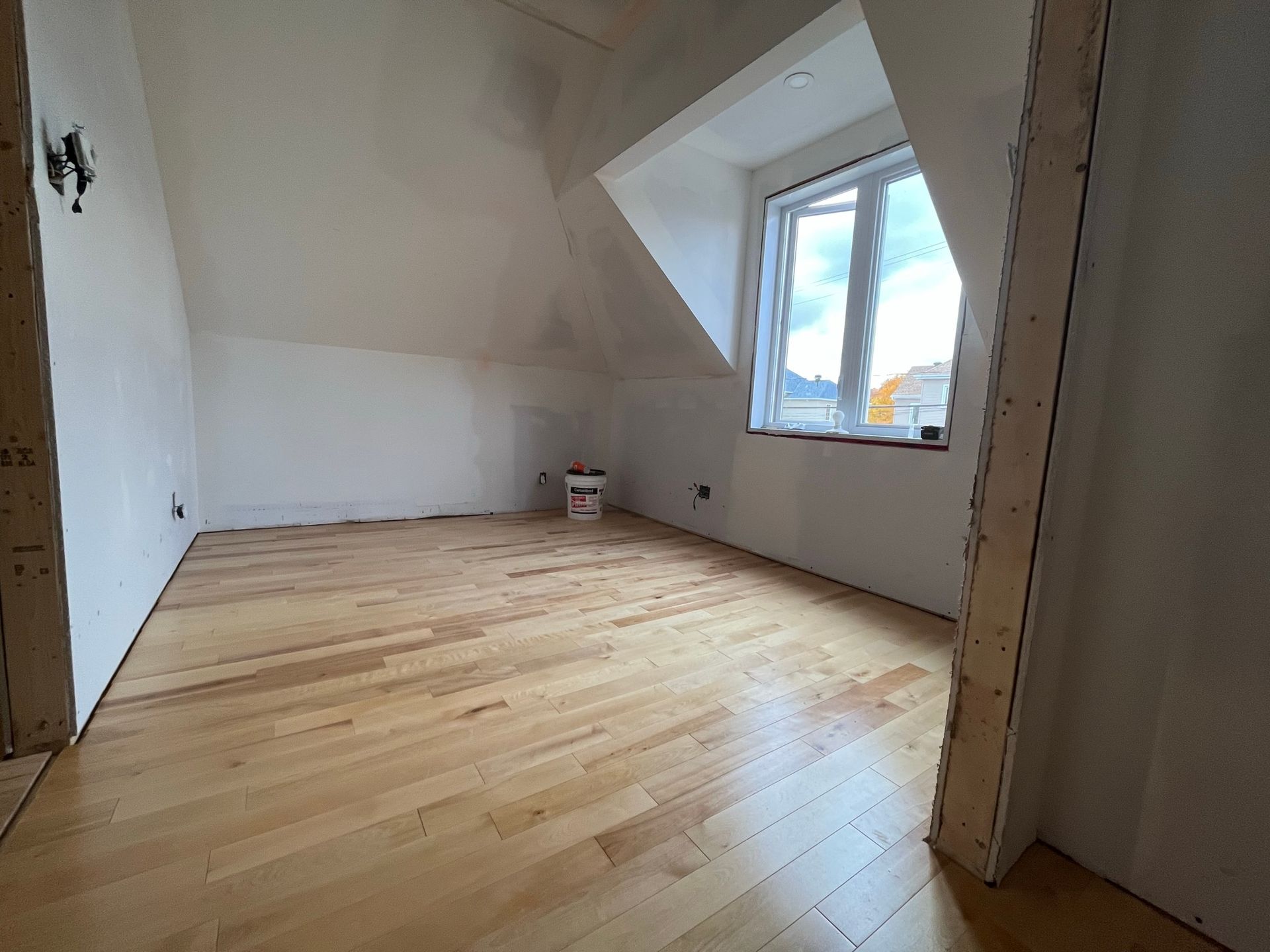 Une pièce vide avec du parquet et une fenêtre.