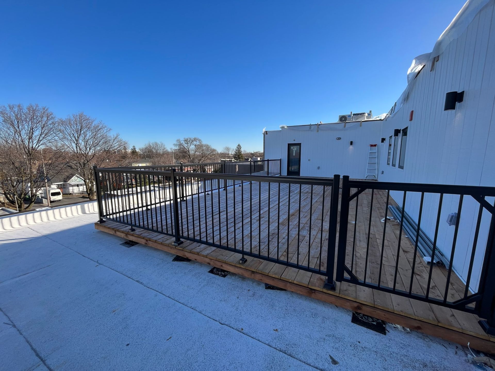 Un balcon avec une balustrade noire et de la neige au sol