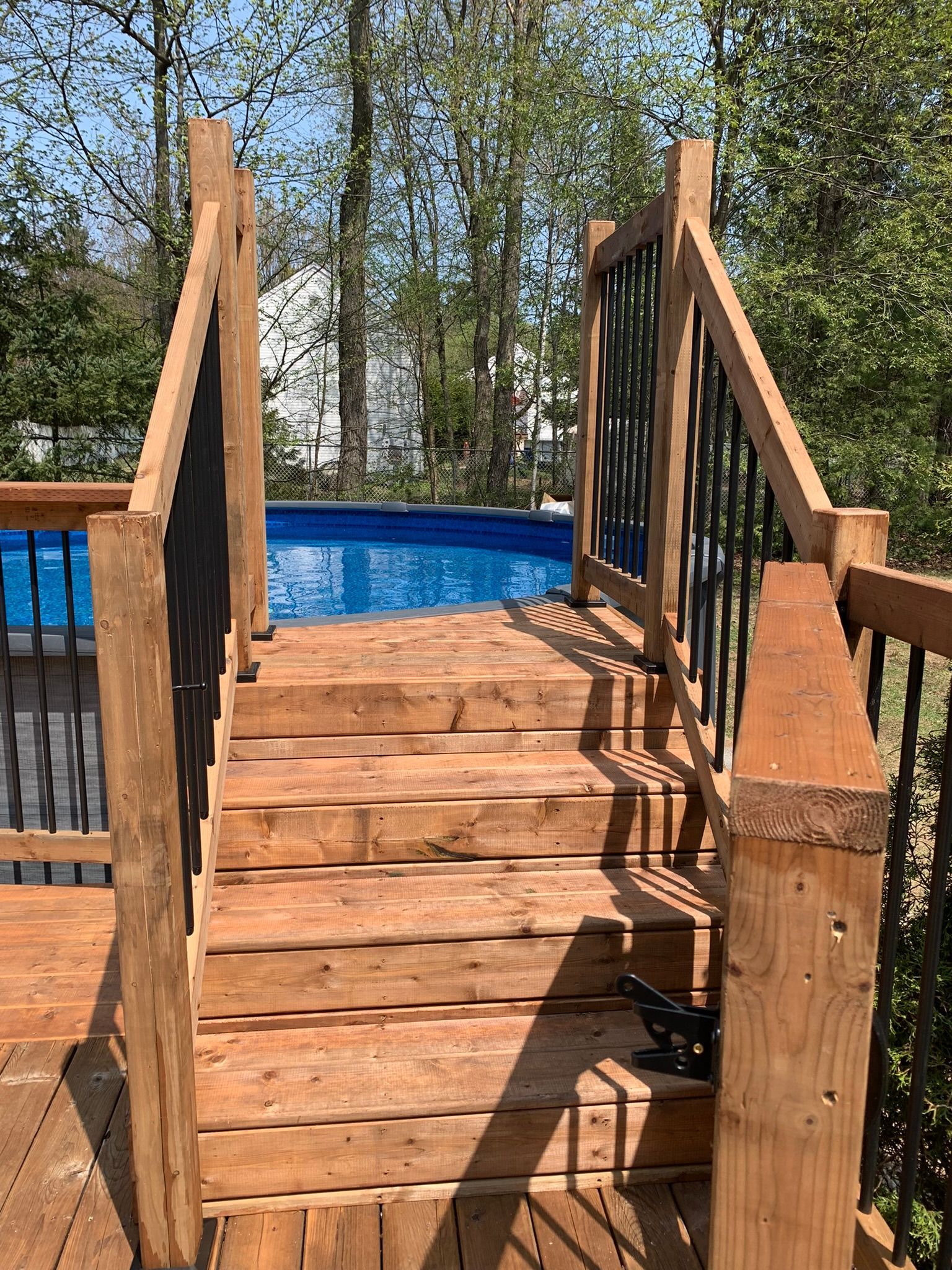 Une terrasse en bois avec escalier menant à une piscine.