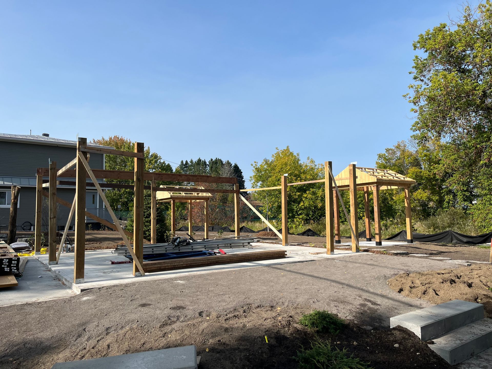 Une structure en bois est en train d'être construite dans la terre devant une maison.
