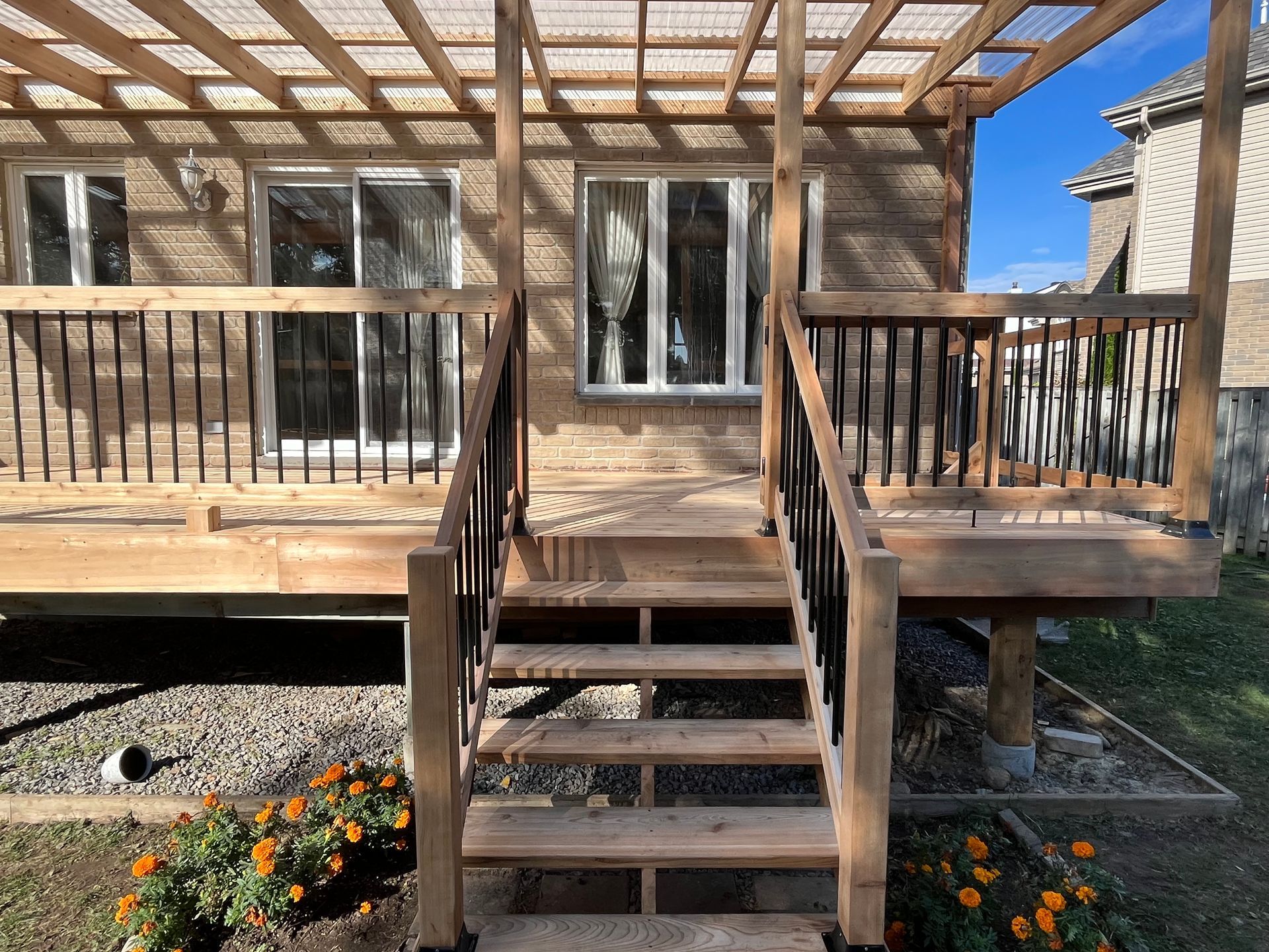 Une terrasse en bois avec des escaliers qui y mènent et une pergola.