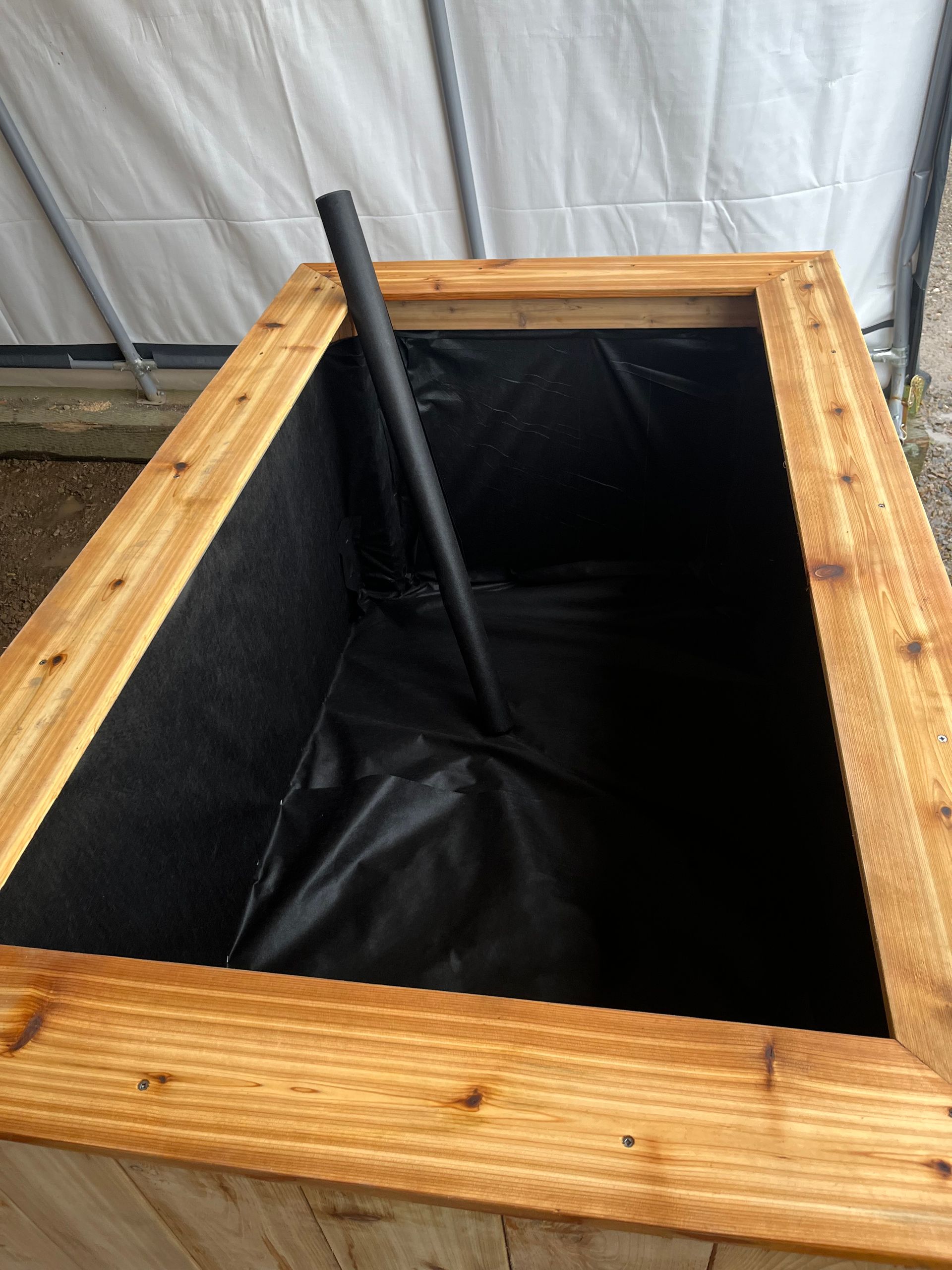 Une jardinière en bois avec une doublure noire et un poteau en métal