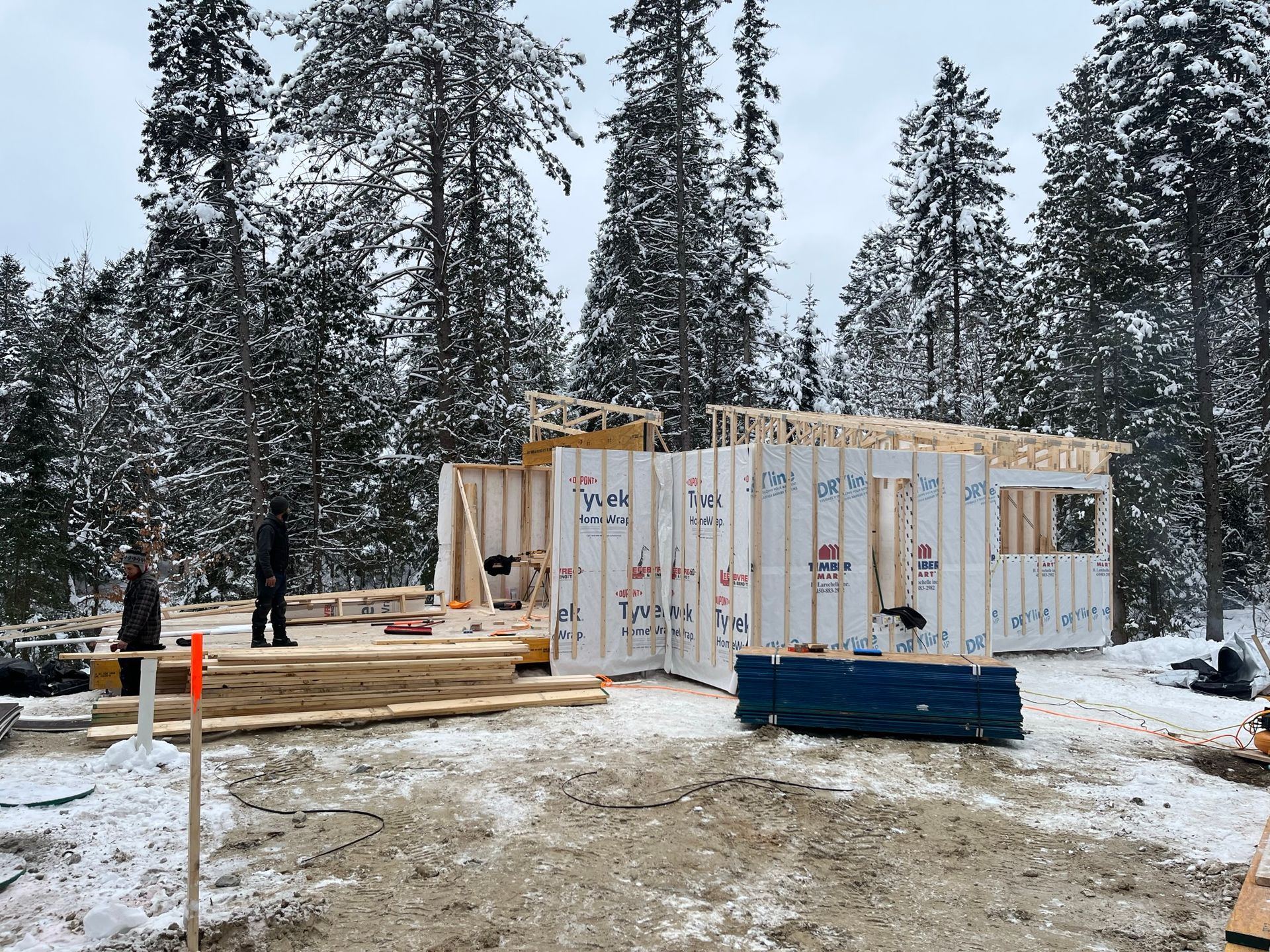Une maison est en construction dans la neige dans les bois.