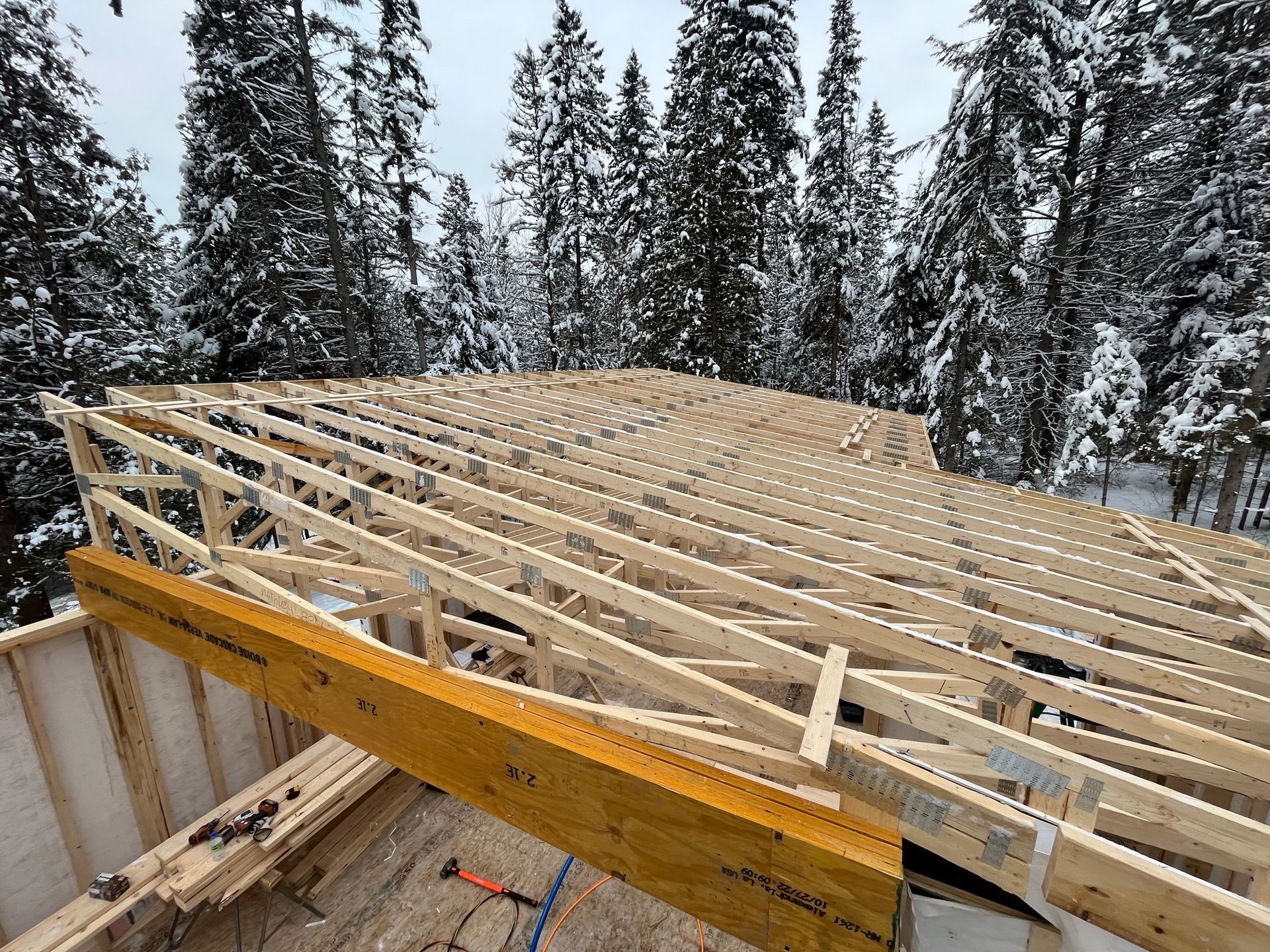 Une structure en bois est en construction au milieu d'une forêt enneigée.