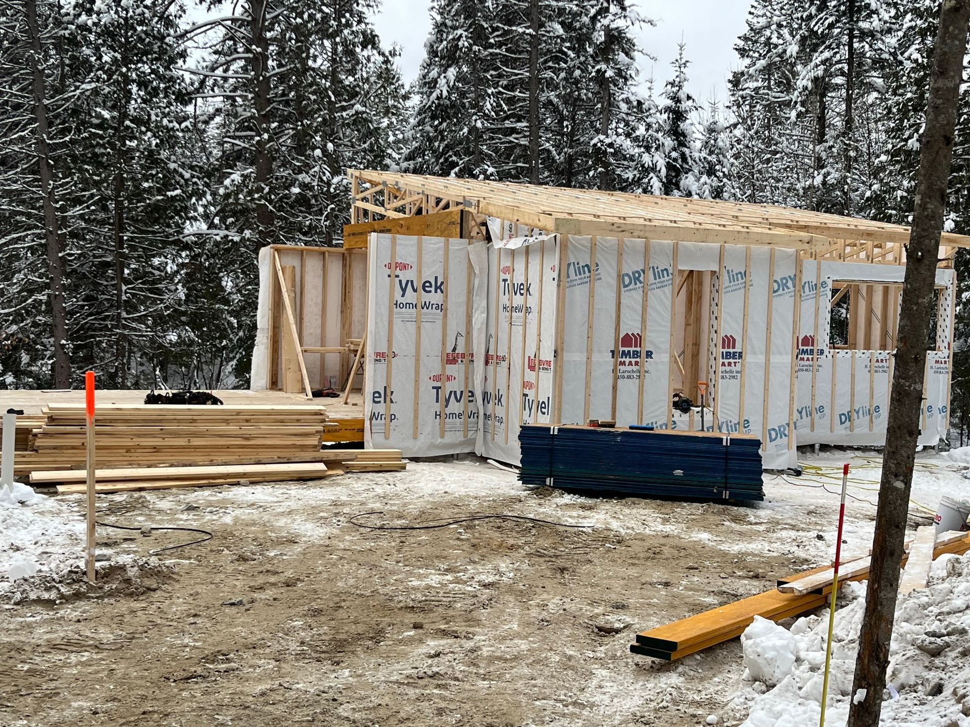 Une maison est en construction dans la neige dans les bois.