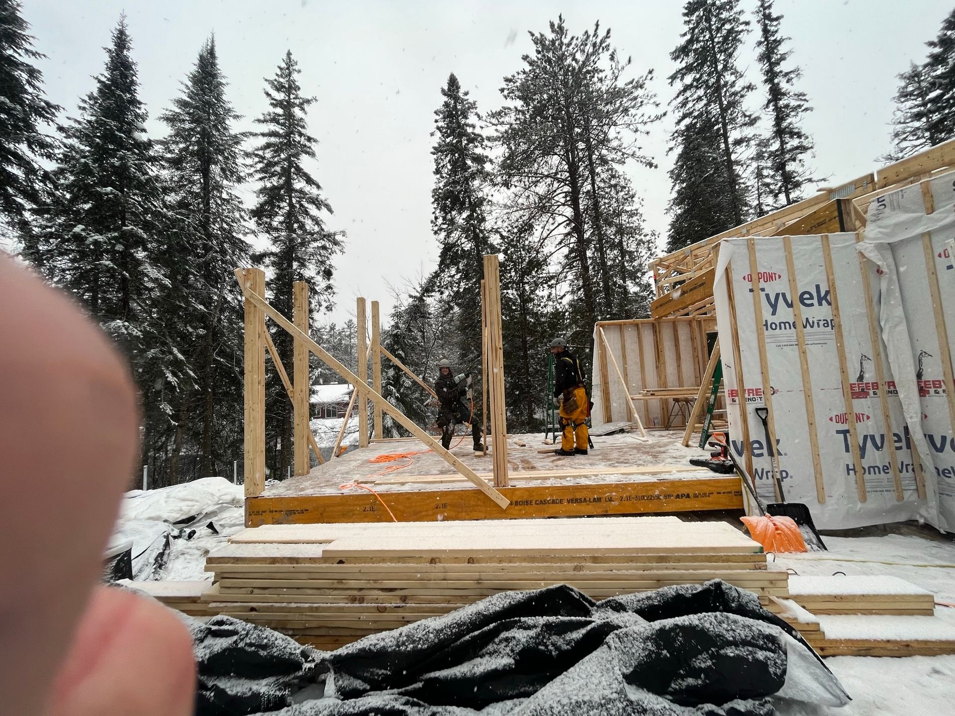 Une personne prend une photo d'une maison en construction dans la neige.