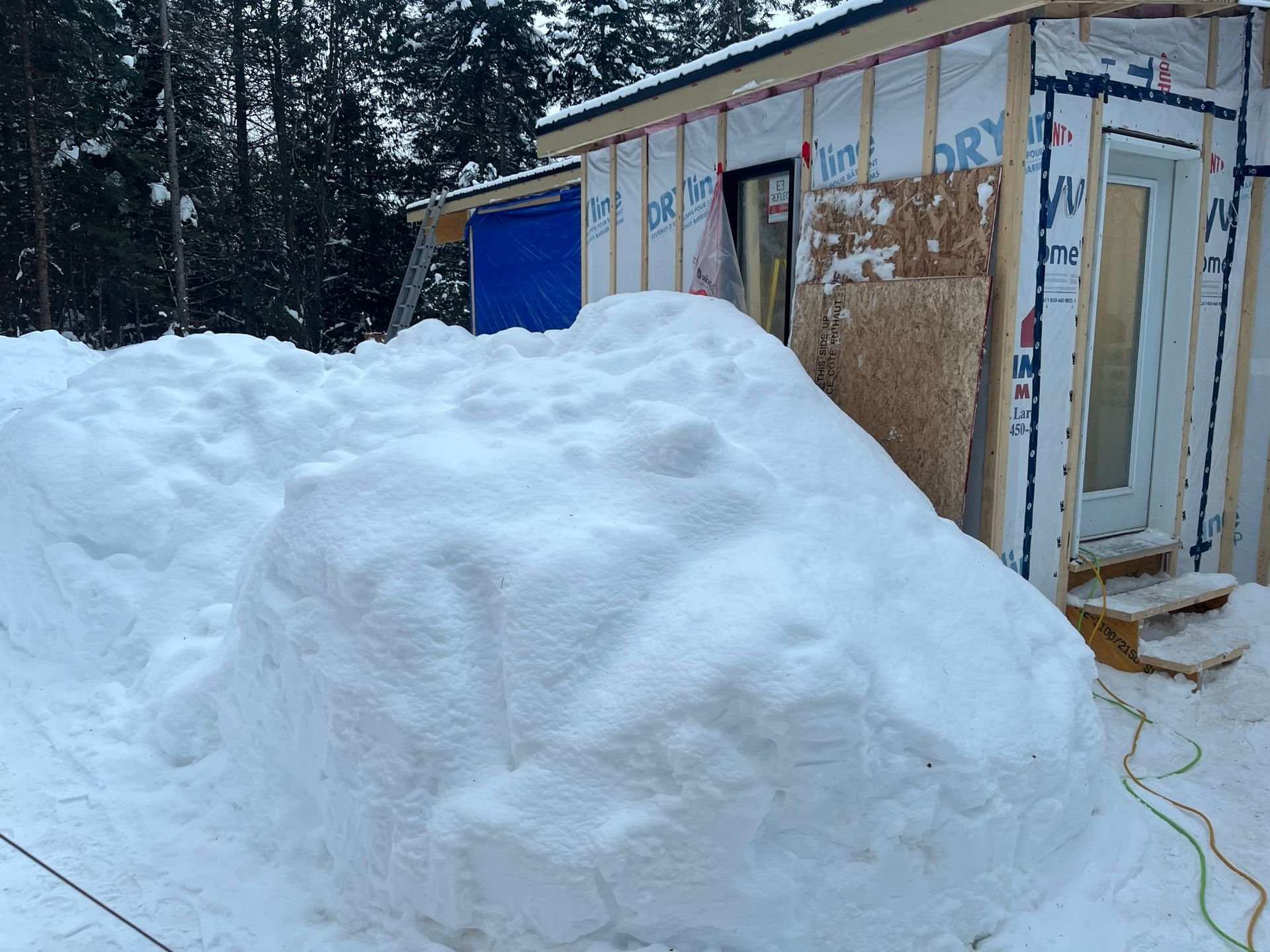 Un gros tas de neige se trouve devant une maison en construction.