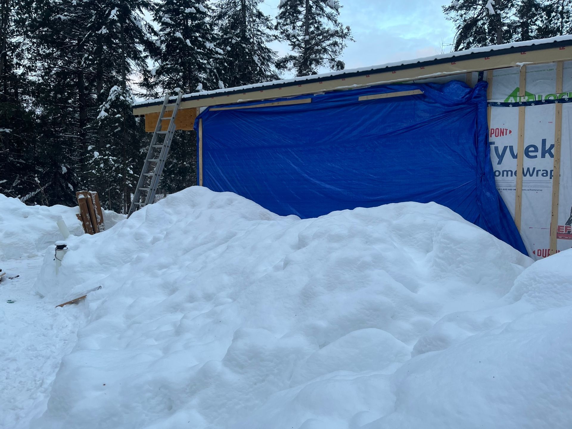 Une bâche bleue recouvre un bâtiment dans la neige