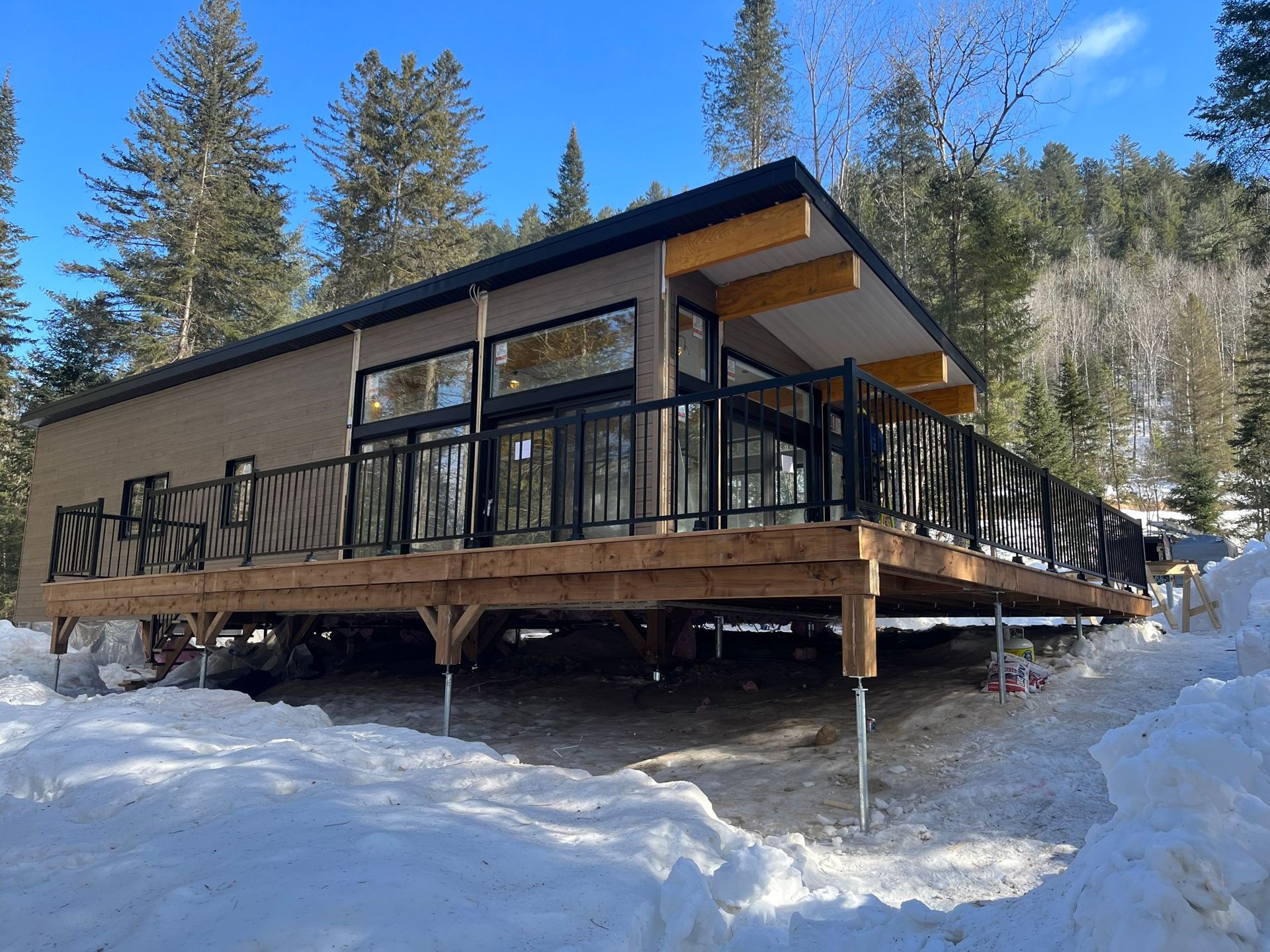 Une maison avec une grande terrasse dans la neige entourée d'arbres.