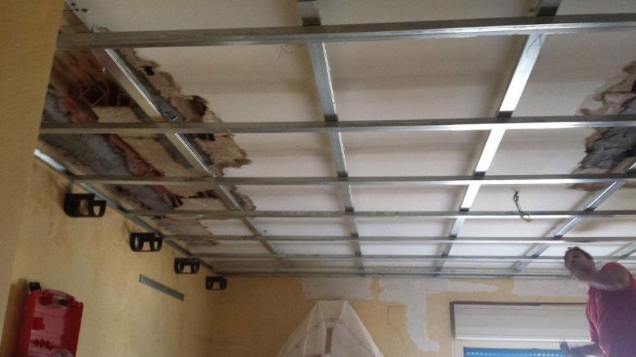 Installata la struttura del controsoffitto in griglia metallica, soffitto danneggiato visibile. Ristrutturazione della stanza in corso.