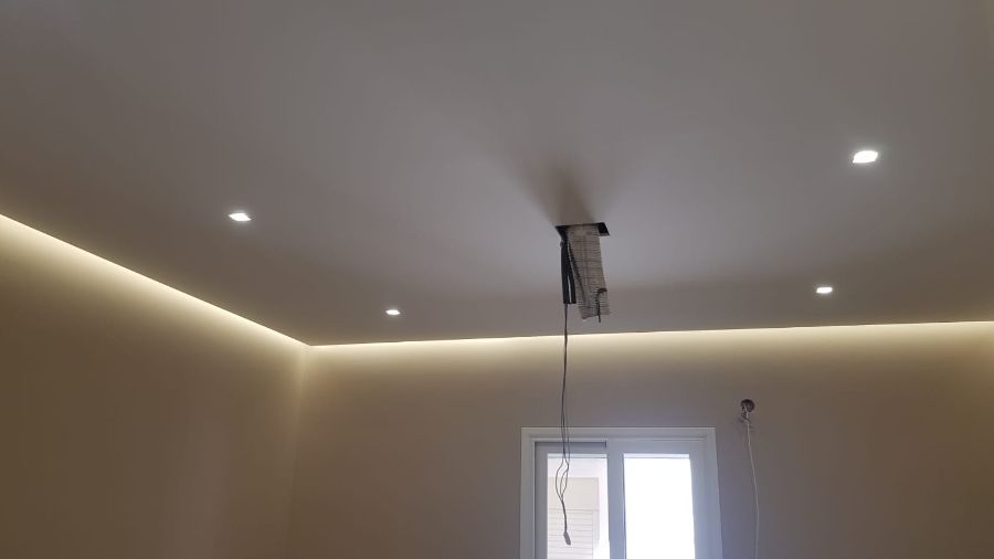 Stanza con illuminazione da incasso e una striscia luminosa nel soffitto. I cavi pendono da un apparecchio.