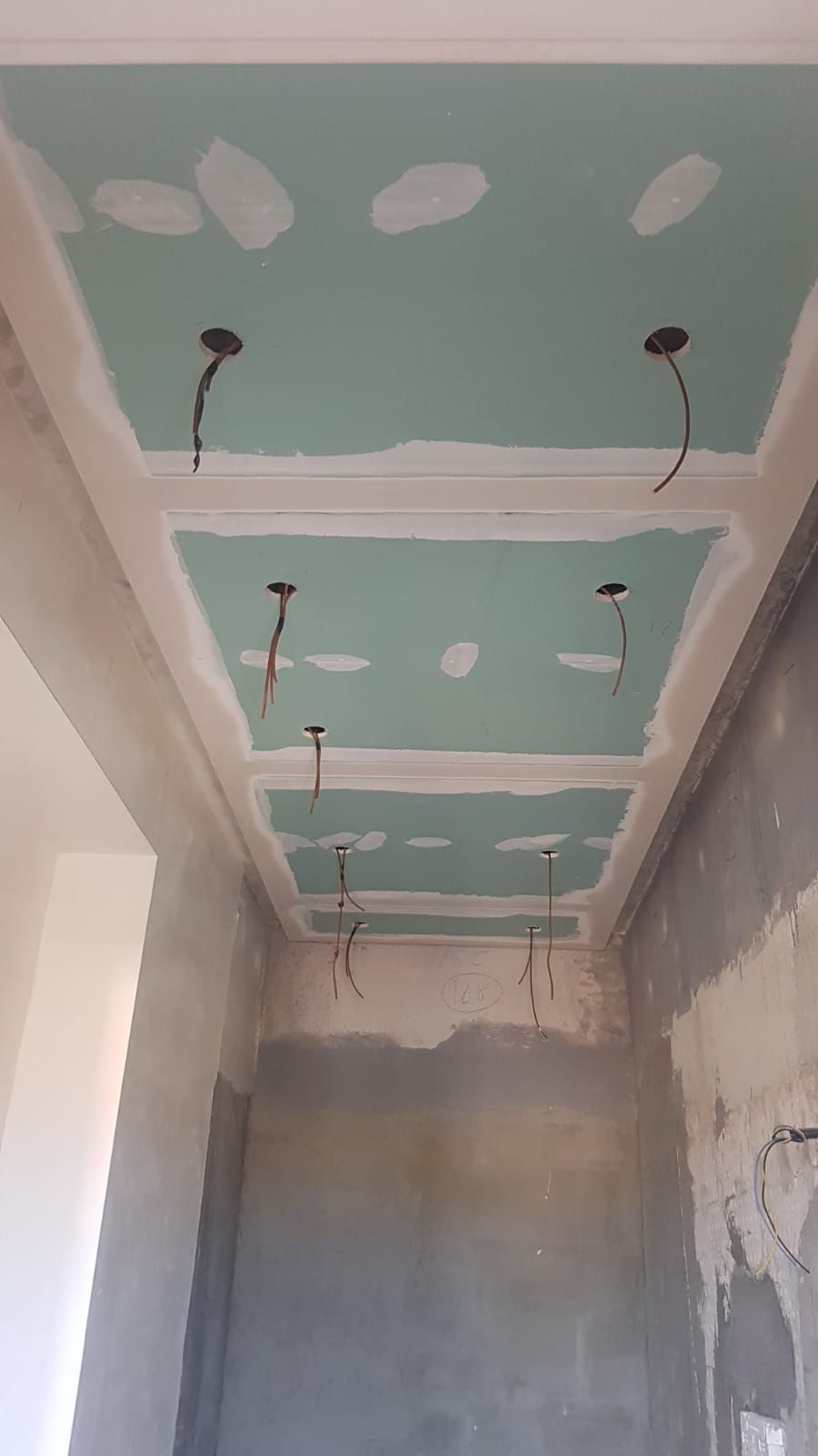 Soffitto in costruzione con pannelli incassati, cavi elettrici esposti e cartongesso fresco.