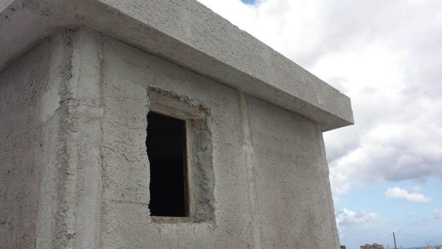 Edificio in cemento con una finestra aperta.